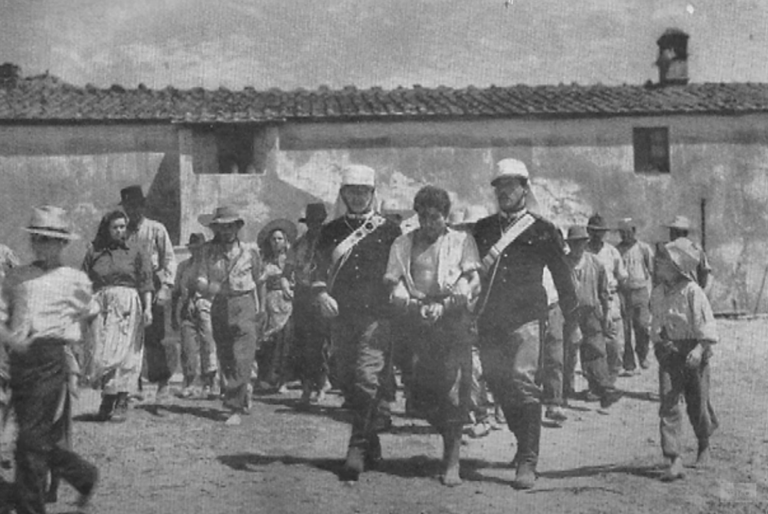 Carabinieri leading Alessandro Serenelli in handcuffs through a crowd after the murder of Maria Goretti